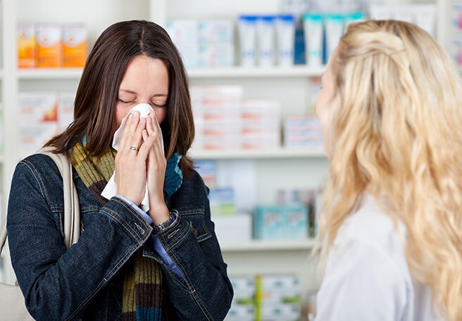 Erkältete Frau in Apotheke Erkältungssymptome
