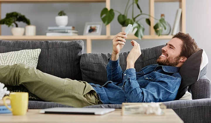 Glücklicher Mann auf dem Sofa Unkomplizierte Einnahme