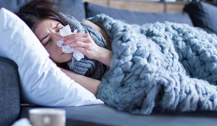 Frau liegt mit Schnupfen im Bett Erkältung mit Schnupfen